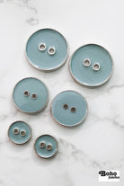 Pale Teal Silver Rimmed Two - hole Buttons. Available in 15mm (24L), 23mm (36L), and 28mm (44L) - Boho Fabrics - Buttons & Snaps